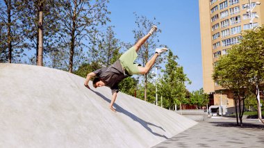 Yer çekimine meydan okuyan genç atletik bir adam bir elinde yanlamasına denge kurarak parkour için beton yamaca karşı gereken gücü gösteriyor. Aktif ve sağlıklı yaşam tarzı kavramı, gençlik kültürü