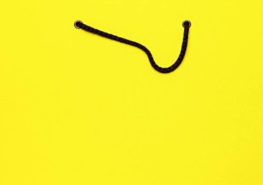 Siyah saplı sarı alışveriş çantasının yakın çekimi alışveriş ve perakende satış kavramını sembolize ediyor. Satış döneminin tanıtımı. Alışveriş kavramı, Kara Cuma, Siber Pazartesi. İlan, metin için boşluk kopyala