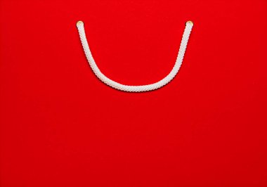 Beyaz saplı kırmızı alışveriş çantasına yakın çekim, alışveriş dönemini ve perakendeciliği sembolize ediyor. Tatil sezonu satışları, hediyeler. Alışveriş kavramı, Kara Cuma, Siber Pazartesi. İlan, metin için boşluk kopyala