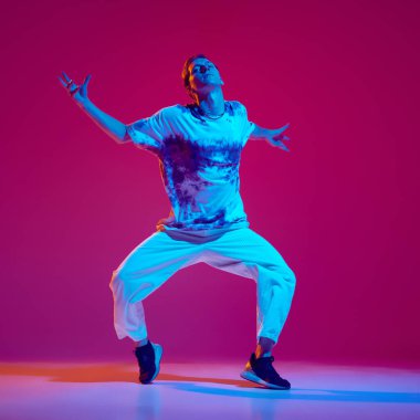 Günlük giysiler içinde genç bir adam, tutkulu ve enerjik bir şekilde hip-hop dansı yapan bir dansçı. Hobi, eğlence, performans, yaratıcılık, yaşam tarzı kavramı