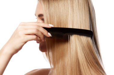 Kusursuz sarı saçlı, beyaz arka planda izole edilmiş düz saçlarını tarayan çarpıcı bir genç kadın. Etkili saç bakımı ve kozmetik ürünleri. Doğal güzellik, saç bakımı, sağlık ve güzellik tedavi kavramı