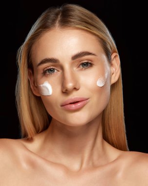 Mükemmel cilde sahip genç güzel bir kadının portresi cilt koruması için spf kremi kullanıyor ve siyah stüdyo geçmişine karşı yaşlanma karşıtı sonuçlar veriyor. Güzellik kavramı, cilt bakımı, kozmetik, sağlık
