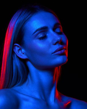 Temiz ciltli güzel bir kadın cilt bakımının sonuçlarını neon ışıkta siyah stüdyo arkaplanıyla karşılaştırıyor. Doğal güzellik kavramı, cilt bakımı, kozmetik, sağlık, kaplıca.
