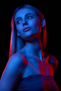 Kusursuz, pürüzsüz cilt gösterme etkisi olan genç ve güzel bir kadın kendini adamış cilt gösterme rutini ile siyah stüdyo arka planına karşı neon ışığı altında. Doğal güzellik kavramı, cilt bakımı, kozmetik, sağlık.
