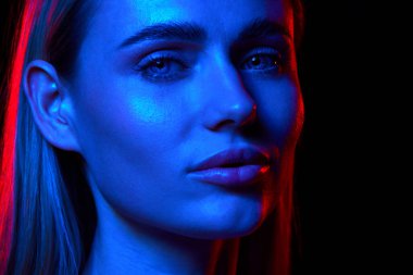 Kusursuz, pürüzsüz cilt gösterme etkisi olan genç ve güzel bir kadın kendini adamış cilt gösterme rutini ile siyah stüdyo arka planına karşı neon ışığı altında. Doğal güzellik kavramı, cilt bakımı, kozmetik, sağlık.