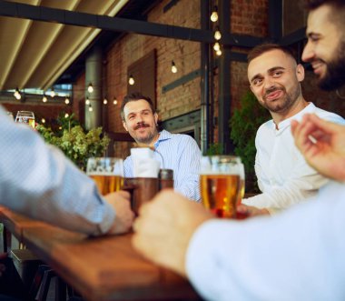 Pozitif adamlar, iş adamları, iş arkadaşları dışarıda barda buluşuyor, konuşuyor, bira içiyor ve işten sonra iyi vakit geçiriyorlar. İş anlayışı, toplantı, kutlama, boş zaman, Ekim Festivali