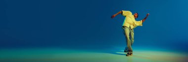 Genç bir adam için dinamik görüntü, hip-hop dansçısı neon renginin değişimine karşı enerjik bir performans sergiliyor. Sokak tarzı kavramı, modern dans, eğlence. Pankart. İlan için alanı kopyala