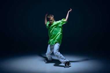 Kot pantolonlu, yeşil tişörtlü, enerjik ve ritimli hip-hop dansı yapan genç bir adam. Sokak tarzı kavramı, modern dans, eğlence
