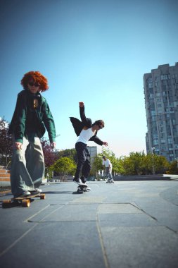 Enerji patlaması. Havalı adamların dinamik görüntüsü, halka açık yerlerde hareket eden patenciler, park, eğitim, kaykay sürme. Spor anlayışı, aktivite ve hareketler, hobi