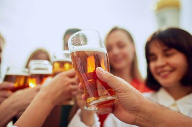 Bir grup arkadaş, Oktoberfest festivalinde kadeh kaldırıyor, tezahürat yapıyor, soğuk bira bardaklarını tokuşturuyor. Dışarıda kutlama var. Cuma havası, kutlama, öğle tatili ve Ekim Festivali kavramı.