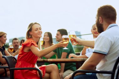Bar terasında oturan, içki içen, uzun yıllar sonra buluşmayı kutlayan bir grup arkadaş. Neşeli bir atmosfer. Cuma havası, kutlama, öğle tatili ve Ekim Festivali kavramı.