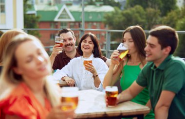 Bar terasında oturan, içki içen, uzun yıllar sonra buluşmayı kutlayan bir grup arkadaş. Neşeli bir atmosfer. Cuma havası, kutlama, öğle tatili ve Ekim Festivali kavramı.
