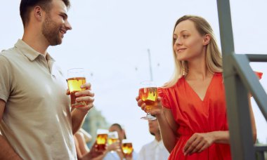 Erkek ve kadın güneşli güzel bir günün tadını çıkarıyorlar. Konuşuyorlar ve dinleniyorlar. Güneşli terasta bira içiyorlar. Neşeli bir atmosfer. Cuma havası, kutlama, öğle tatili ve Ekim Festivali kavramı.