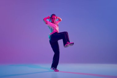 Dans okulu. Şık ve sanatsal genç kız, neon ışıkta, değişken mor arka plana karşı duygularla hip hop dansı yapıyor. Serbest stil dansı, modernlik, şehir kültürü, gençlik kavramı