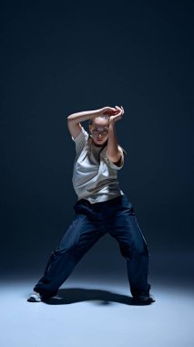 Artistik ve etkileyici genç kız, enerji dolu, deniz mavisi stüdyo geçmişine karşı tutkulu bir şekilde hip-hop dansı yapıyor. Serbest stil dansı, modernlik, şehir kültürü, gençlik kavramı