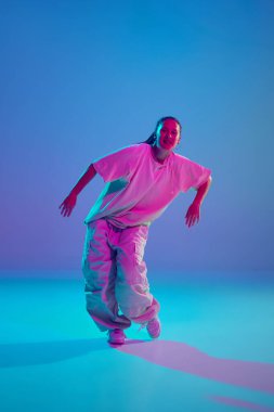 Müzik dürtülerinin ritmini yakalamak, neon ışığın altında hip-hop dansı yapan genç artistik kız. Serbest stil dansı, modernlik, şehir kültürü, gençlik kavramı