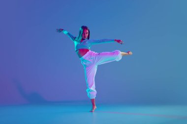 Dans kulübü üyesi. Genç, yetenekli ve etkileyici bir kız. Dansçı, neon ışıkta, gradyan mavi arka plana karşı enerjik bir hip hop performansı sergiliyor. Serbest stil dansı, modernlik, şehir kültürü kavramı