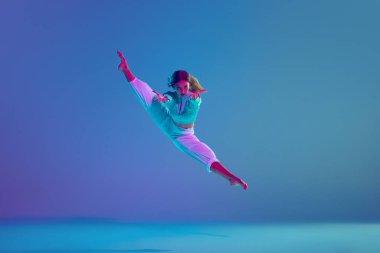 Esnek genç bir kız, tutkulu bir hip hop dansçısı sahnede, neon ışıkta, değişken mavi arka plana karşı dinamik hareketler yapıyor. Serbest stil dansı, modernlik, şehir kültürü, gençlik kavramı