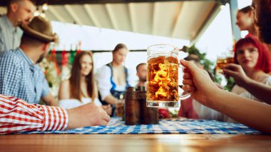 Bira bardağına odaklan ve bulanık insanlara, barda oturan arkadaşlara ve kutlamaya, içmeye, konuşmaya. Ekim Festivali, festival, parti, bira fabrikası, gelenek kavramı