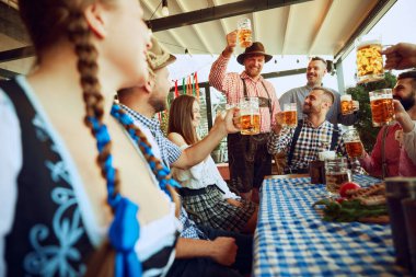 Neşeli bir grup insan, kutlama için barda toplanan arkadaşlar, bira içmek, kadeh tokuşturmak ve etrafa neşe saçmak. Ekim Festivali, festival, parti, bira fabrikası, gelenek kavramı