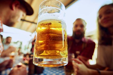 Arka planda bulanık insanların olduğu bira bardağına odaklan. Neşeli bir kutlama için barda toplanan bir grup insan. Ekim Festivali, festival, parti, bira fabrikası, gelenek kavramı