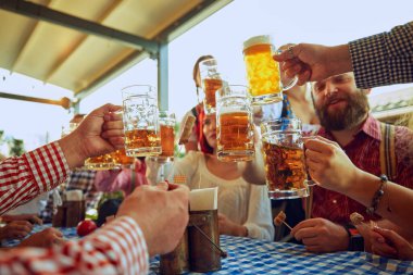 Neşeli insanlar, arkadaşlar, erkek ve kadınlar yerel bir barda oturuyor, bira içiyor ve rahatlatıcı bir hafta sonu geçiriyorlar. Ekim Festivali, festival, parti, bira fabrikası, gelenek kavramı