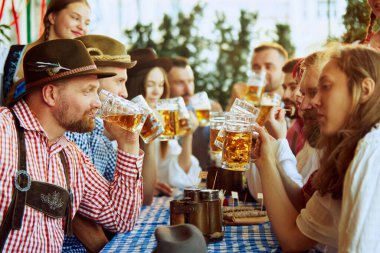 Bir grup insan, kadın ve erkek barda buluşuyorlar, keyifle bira içiyorlar. Geleneksel bira festivali. Ekim Festivali, festival, parti, bira fabrikası, gelenek kavramı