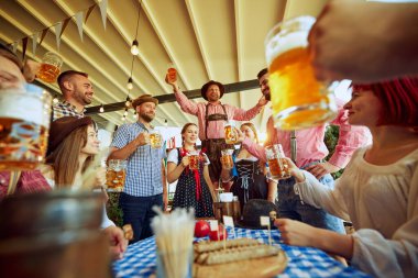 Geleneksel Bavyera kıyafetleri içindeki erkekler, arkadaşlarının tezahürat grubu, insanlar bira festivali için yerel bir barda buluşuyorlar. Ekim Festivali, festival, parti, bira fabrikası, gelenek kavramı