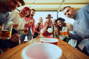 Bir grup insan neşeyle bira pong oynuyor, bira festivalini kutlarken barda eğleniyor. Bavyera gelenekleri. Ekim Festivali, festival, parti, bira fabrikası, gelenek kavramı