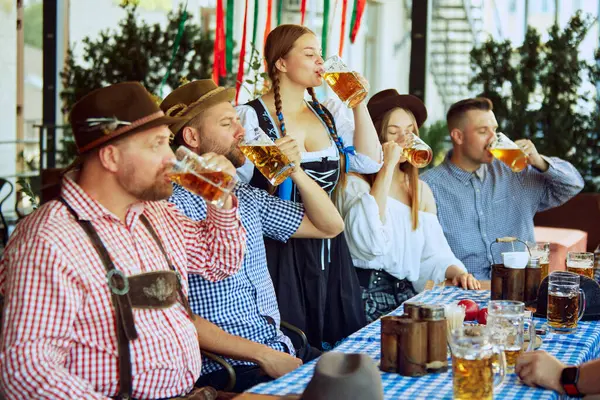 Bir grup insan, kadın ve erkek barda buluşuyorlar, keyifle bira içiyorlar. Geleneksel bira festivali. Ekim Festivali, festival, parti, bira fabrikası, gelenek kavramı