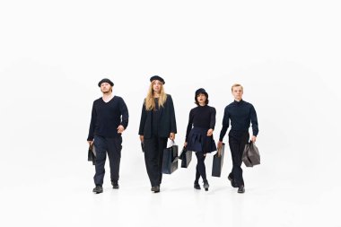 Tarz sahibi bir grup insan, hepsi siyah kıyafetler içinde ellerinde alışveriş torbalarıyla, beyaz arka planda izole bir şekilde rahatça yürüyorlar. Alışveriş, satış, Kara Cuma, moda, tatil kavramı