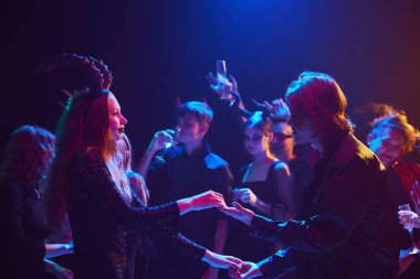 Gençlerle dolu bir gece kulübünde canlı bir Cadılar Bayramı partisi sahnesi, kostümlü ve makyajlı arkadaşlar olun, bayramı neşe ve neşeyle kutlayın, gülün ve dans edin. Cadılar Bayramı kavramı, tatil, parti, eğlence