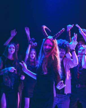 Yaratıcı Cadılar Bayramı kostümlü bir grup arkadaş kahkaha ve müzikle kutlama yapıyor loş ışıklı gece kulübünde neşeyle dans ediyorlar. Cadılar Bayramı kavramı, tatil, parti, eğlence