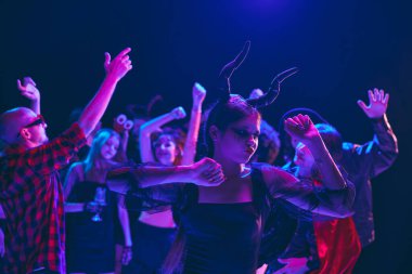 Cadılar Bayramı partisi sahnesi neşeli genç kızlar ve oğlanlar, çeşitli kostümler giyen, ürkütücü makyajlı, gece kulübünde neşeli danslar yapan öğrenciler. Cadılar Bayramı kavramı, tatil, parti, eğlence