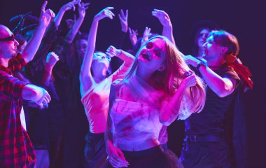 Gençler, oğlanlar ve kızlar çeşitli Cadılar Bayramı kostümleriyle, hayaletlerden perilere, gece kulübünde dans ederek, kutlama yaparak, gülerek ve eğlenerek. Cadılar Bayramı kavramı, tatil, parti, eğlence