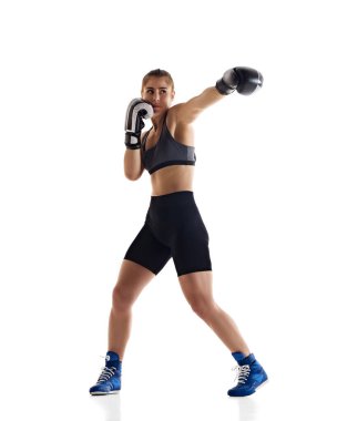 Yumruk at. Yoğunlaşmış genç bir kadının, hareketli bir boks atletinin beyaz stüdyo arka planında izole edilmiş bir şekilde çalışmasının tam boy görüntüsü. Spor anlayışı, hobi, aktif ve sağlıklı yaşam tarzı