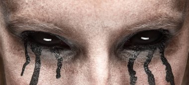 Perili, siyah gözlü, siyah gözlü, yanaklarından süzülen gözyaşı damlaları, korku ve gizem hissi yayıyor. Cadılar Bayramı kavramı, makyaj, doğaüstü karakter. Broşür, afiş.