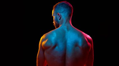 Arka planda, genç bir adamın tanımlanmış vücudunu, kaslı vücudunu, neon ışıkta arka plandaki siyah stüdyoya karşı güçlü sırtını gösteren görüntüsü var. Erkek güzelliği, cilt ve vücut bakımı, hijyen, spor