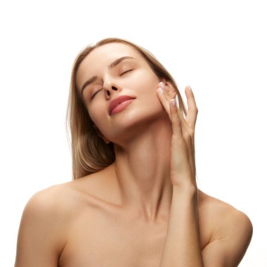 Zarif ve zarif genç bir kadının portresi lekesiz, pürüzsüz ciltli, gözleri kapalı beyaz arka planda poz veriyor. Doğal güzellik, cilt bakımı, kozmetik ve kozmetik kavramı