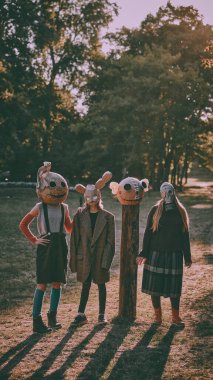 Ürkütücü maskeli ve garip elbiseli bir grup insan sonbahar ormanlarında dikilip korkunç bir tatil atmosferi yaratıyorlar. Ürkütücü Cadılar Bayramı atmosferi. Cadılar Bayramı kavramı, ürkütücü sezon, eski tarz..