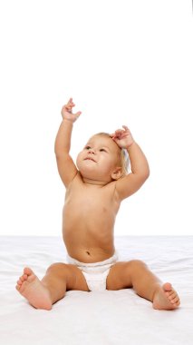 Mutlu bir kız bebek, beyaz bir battaniyeye oturmuş, elleri heyecanla kalkıyor, çocukluk döneminin neşe, büyüme ve oyuncu tarafını temsil ediyor. Çocukluk kavramı, annelik, bakım