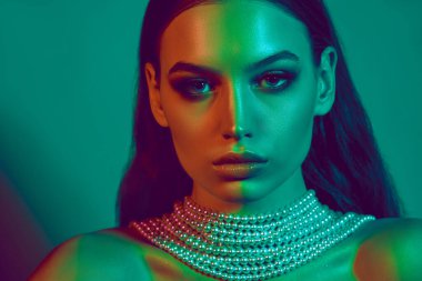 Çift tonlu yeşil ve mavi ışık altında genç güzel bir kadının yakın plan portresi kusursuz cildini ve çarpıcı özelliklerini vurguluyor. Kadın güzelliği, sanat, moda makyaj, parti kavramı