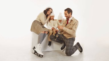 Baba, genç kızına buz patenlerini bağlamada yardım ediyor. Mutlu bir ailenin birlikte vakit geçirdiği samimi bir an. Aile kalın kışlık giysiler giyiyor. Kış, tatil, tatil, boş zaman aktivite kavramı