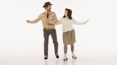 Tarz sahibi bir kadın ve erkek birlikte vakit geçiriyorlar, buz pateni beyaz arka planda izole edilmiş. Şık, kalın giysiler giyen bir çift. Kış kavramı, tatil, tatil, boş zaman aktivitesi