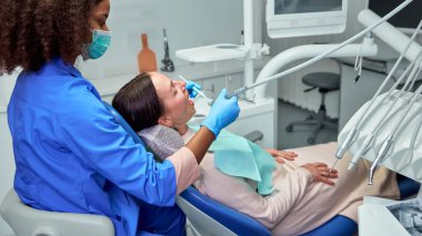 Diş hekimi, özel diş ihtiyaçlarını giderirken, hasta konforuna odaklanarak, nazik bir tedavi uygulamak için gelişmiş araçlar kullanır. Sağlık sigortası, güzellik, hijyen, dişçi danışmanlığı kavramı.