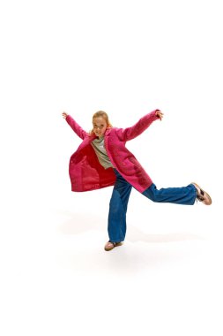 Tarz sahibi küçük kız beyaz stüdyo geçmişine karşı neşeli bir ifadeyle el ve bacak kaldırıyor. İş anlayışı, meslek anlayışı, insan duyguları ve yüz ifadeleri. Ad