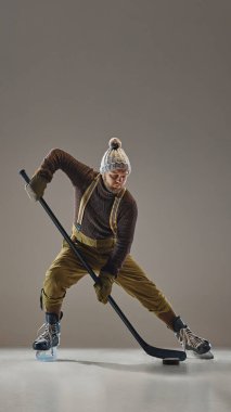 Hokey oyuncusu örgü, şapka, süveter, pantolon ve pantolon çubukla hareket ediyor. Odaklanma ve beceri gösteriyor. Spor, oyun, turnuva, aksiyon, yarışma kavramı