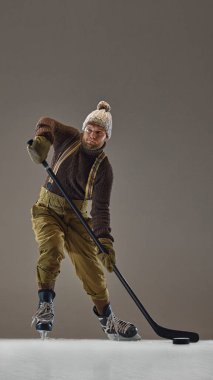 Dikey olarak, örgü süveter, askılı şapka ve pantolon giyen hasta ve hokey oynayan bir adamın görüntüsü. Spor, oyun, turnuva, aksiyon, yarışma kavramı