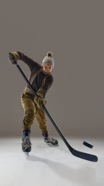 Pantolon ve pantolon giyen, kalın süveter ve şapka ören, sopayla hareket eden, diske vuran bir adam. Kış sporları ve aktiviteleri. Spor, oyun, turnuva, aksiyon, yarışma kavramı