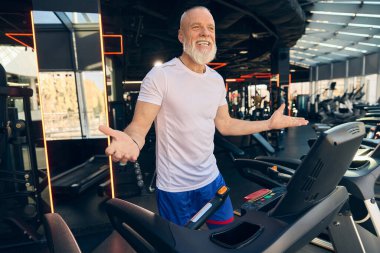 Koşu bandındaki mutlu son sınıf öğrencisi, beden eğitimi seansında gülümsüyor. Fitness rutinlerinde sağlıklı yaşam ve pozitiflik için motivasyon. Yaşlıların konsepti, spor, aktif yaşam tarzı, sağlık